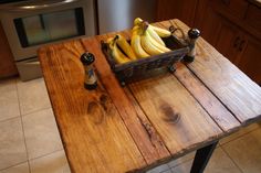 a wooden table topped with bananas next to a bottle of beer on top of a tile floor