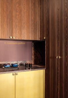 a kitchen with yellow cabinets and brown counter tops, along with wooden wall paneling