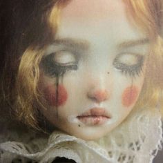 a close up of a doll's face with eyes closed and blood smeared on her cheek