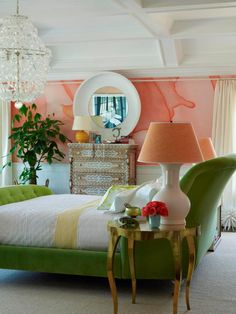 a bedroom decorated in pink, green and white with an oval mirror on the wall