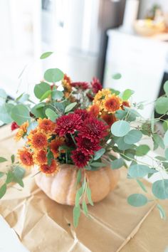 a vase filled with lots of flowers sitting on top of a brown paper covered table