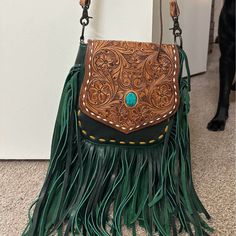 a brown and green purse sitting on top of a floor next to a black dog