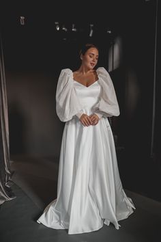 a woman in a white wedding dress is standing with her hands on her hips and looking off to the side