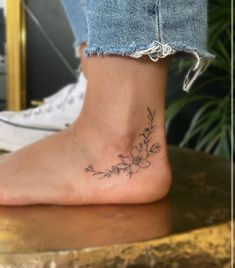 a woman's foot with a small flower tattoo on the side of her ankle