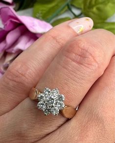 a woman's hand with an engagement ring on it and flowers in the background