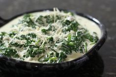 a black bowl filled with cheese and greens