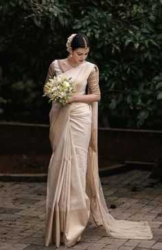 a woman in a white sari holding a bouquet