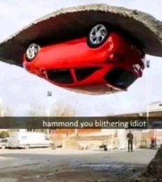 a red car is suspended upside down in the air