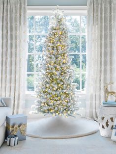 a decorated christmas tree sitting in the corner of a living room next to a window