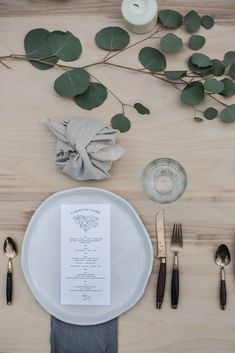 the place setting is laid out with silverware, napkins, and greenery