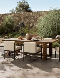 an outdoor dining table with four chairs and a bowl of fruit on the table next to it