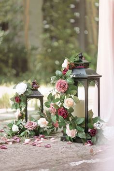 two small lanterns with flowers on them next to each other and one candle in the middle