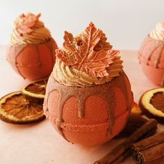 three pumpkins decorated with cinnamon and icing on a table next to orange slices