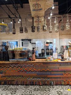 the interior of a coffee shop with lots of cups hanging from the ceiling and colorful rugs on the floor