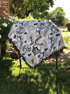 a white and black blanket sitting on top of a metal stand in the grass next to flowers