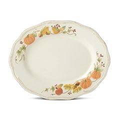 a white plate with pumpkins and leaves painted on the rim, sitting against a white background