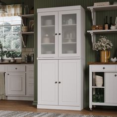 a kitchen with green walls and white cupboards in the corner, along with a rug on the floor