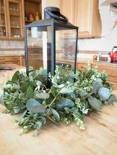 a lantern is sitting on top of a table with some greenery in front of it