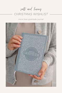 a woman holding a blue book with the words gratitude written on it