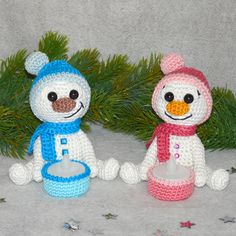 two crocheted snowmen sitting next to each other in front of a christmas tree