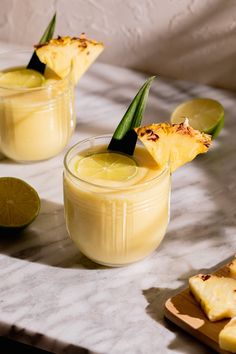 two glasses filled with pineapple margaritas and garnished with lime wedges