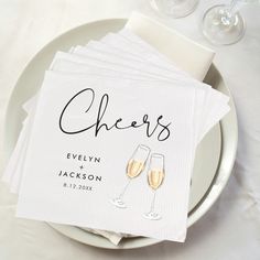 personalized napkins with champagne glasses are on a plate next to two wine glasses