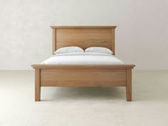 a wooden bed frame with white sheets and pillows