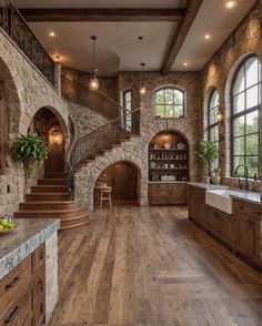 a large kitchen with wood floors and stone walls, along with an arched doorway that leads to the second floor