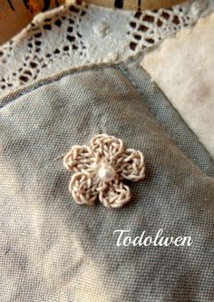 a small crocheted flower is on top of a piece of fabric with the word today written below it