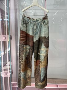 a pair of jeans hanging on a hanger in front of a glass case with an open door