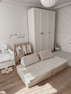 a large white couch sitting in a bedroom next to a baby crib and dresser