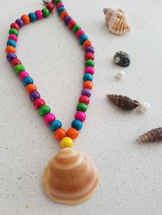 A handcrafted necklace featuring natural sea shells and a variety of colorful beads. An ideal gift for any occasion, it pairs well with any outfit. Bohemian Shell With Colorful Beads For Gift, Multicolor Beaded Shell For Beach, Handmade Multicolor Shell For Vacation, Bohemian Beaded Multicolor Shell, Bohemian Multicolor Beaded Shell, Colorful Wooden Beads Jewelry For Beach, Beaded Multicolor Shell As Gift, Colorful Wooden Beads Necklace For Beach, Multicolor Beaded Shell As A Gift