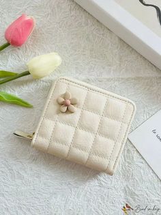 three tulips sitting next to a white purse on a table with a card holder