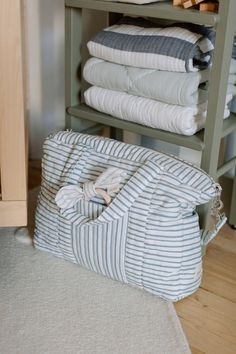 several folded towels are stacked up on a shelf next to a pile of folded blankets