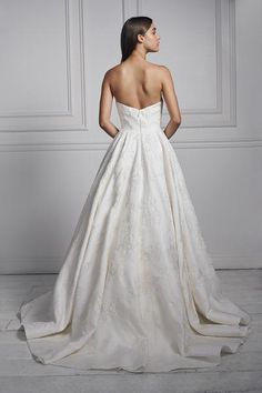 a woman in a white wedding dress looking off into the distance with her back to the camera