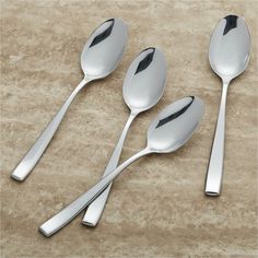 three silver spoons and two forks on a marble counter top with a beige background