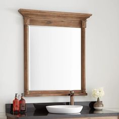 a bathroom with a sink and mirror on top of the counter next to a vase