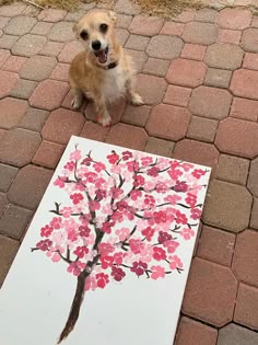 a dog sitting next to a painting on the ground