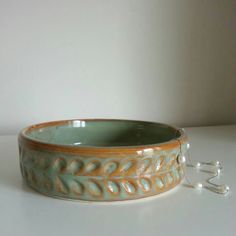 a ceramic bowl sitting on top of a white table next to a silver chain hanging from the wall