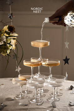 champagne being poured into wine glasses on top of a table with confetti and stars