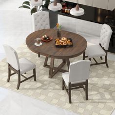 a round table with white chairs around it and plates of donuts on the table