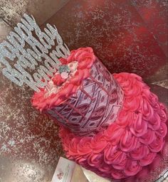 a birthday cake with pink and red frosting on it's top, sitting on a pedestal