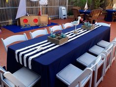 a table set up for an outdoor party with blue and white striped cloths on it