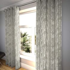 an open window with curtains and a chair in front of it on a hardwood floor