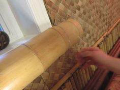 a person is touching the bamboo on top of a wooden structure in front of a window