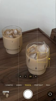 two glasses filled with liquid sitting on top of a wooden table next to each other