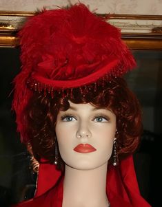 Embrace the grandeur of Victorian-era fashion with this captivating Red "Rosalie" French Fashion Hat from East Angel Harbor Hats. Handcrafted with attention to detail and precision by Darna, this striking hat is sure to draw admiration wherever you go. Show off your style and express your sophistication effortlessly with this gorgeous red wool hat. The brim is delicately accented with French-style red teardrop beads and red gimp which adds a delightful shine to the whole ensemble. The hat band i Traditional Fitted Costume Hats And Headpieces, Elegant High Crown Headpiece For Costume, Elegant Top Hat For Kentucky Derby Costume, Elegant Wide Brim Costume Hat, Red Vintage Costume Hat, Red Fitted Hat For Costume, Elegant High Crown Mini Hats For Costume, Elegant Fitted Mini Hats For Costume, Elegant Fitted Top Hat For Costumes