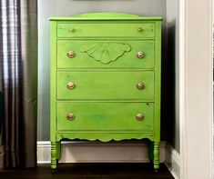 a green chest of drawers sitting next to a painting on the wall in a room