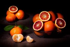 a basket filled with oranges sitting on top of a wooden table next to slices of grapefruit