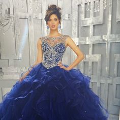 a woman in a blue ball gown posing for the camera with her hands on her hips